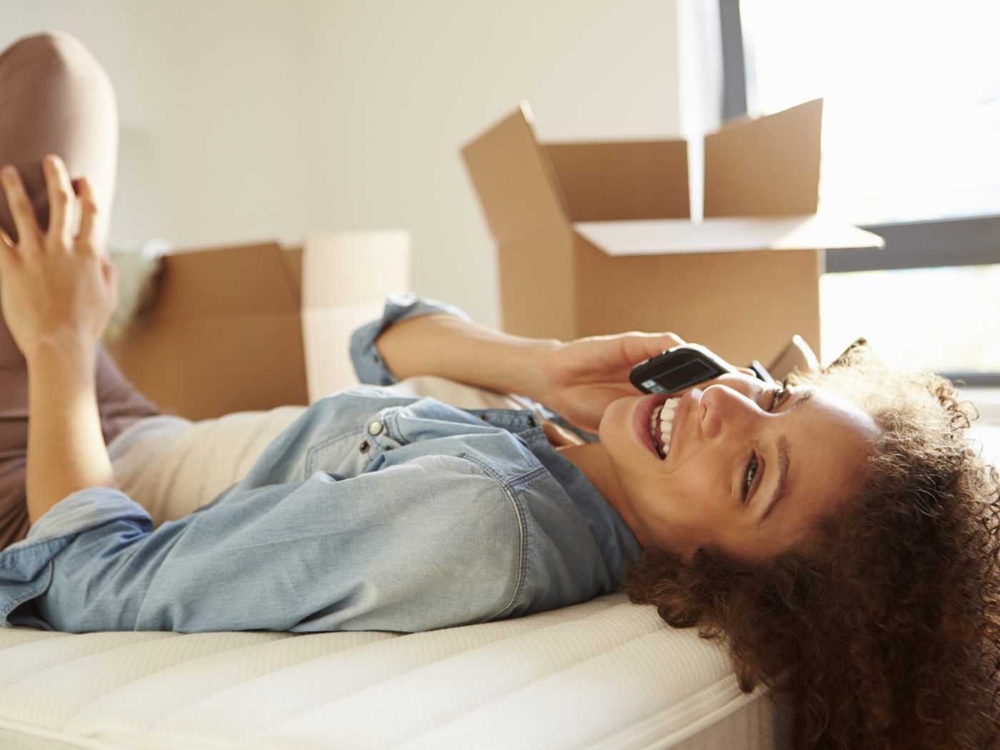 Woman Moving Into New Home Talking On Mobile Phone