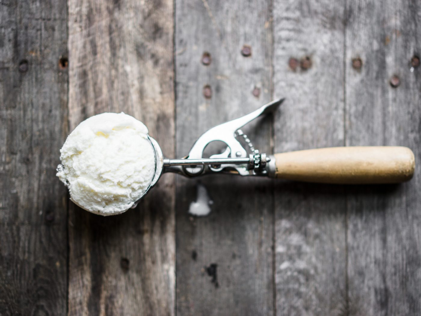 Scoop of vanilla ice-cream on rustic wooden background