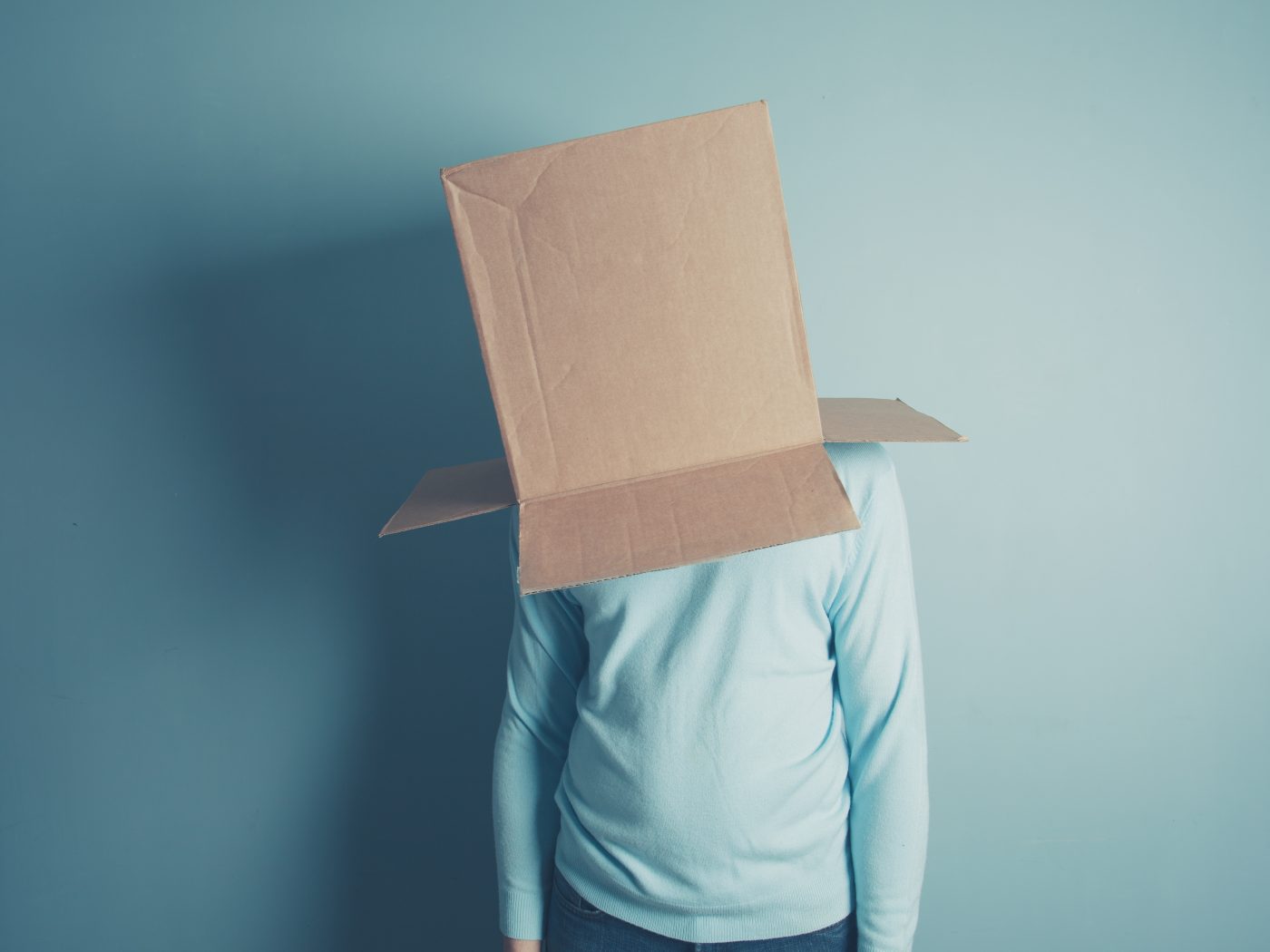 A man is standing with a cardboard box over his head