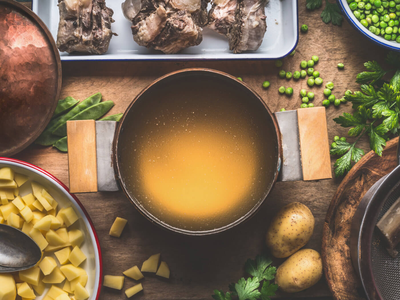Pot with meat broth , cooking preparation for potatoes soup with green peas, top view
