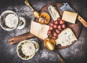 Appetizing fine cheese selection on rustic plate with wine, grape and Honey mustard sauce , top view