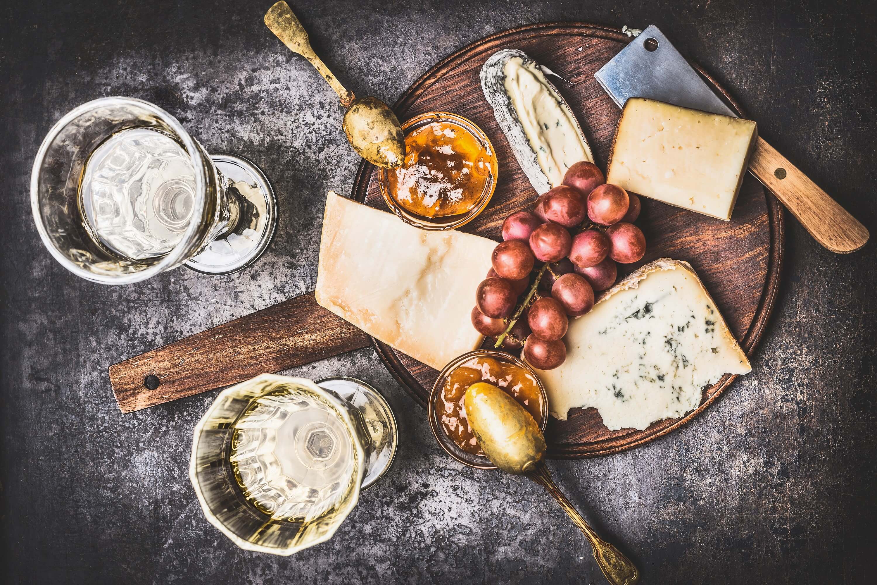 Appetizing fine cheese selection on rustic plate with wine, grape and Honey mustard sauce , top view