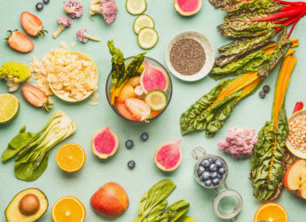 Healthy food ingredients flat lay with various fruits , vegetables, seeds and nut on light mint background. Mixer for detox drinks making, top view. Dieting and clean eating concept
