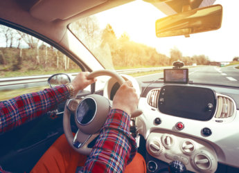 roadtrip - mans hands on the wheel and autobahn in the background